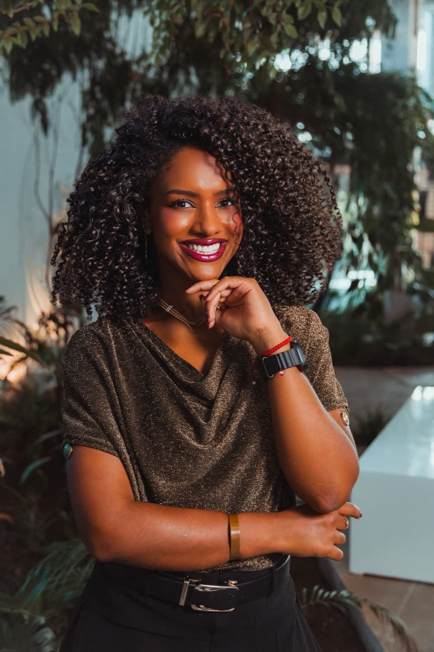 Jéssica Alexandre sorrindo em um jardim, luz dourada